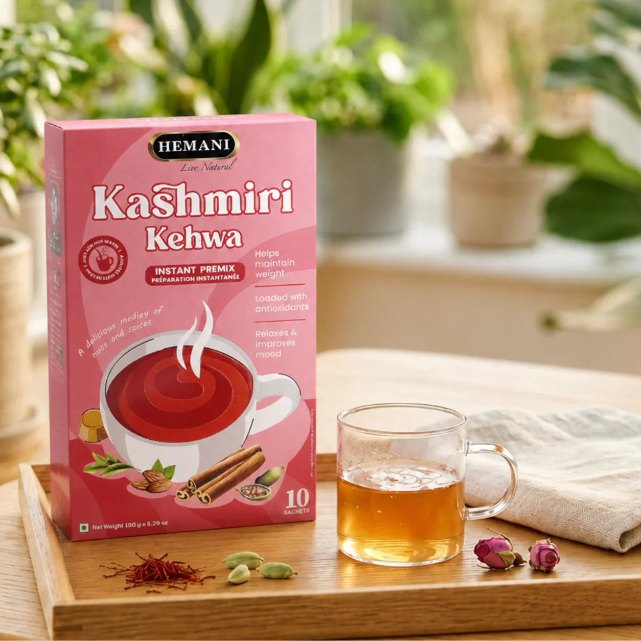 Hemani Kashmiri Kehwa instant herbal tea box with brewed tea, spices, and rose buds on wooden tray