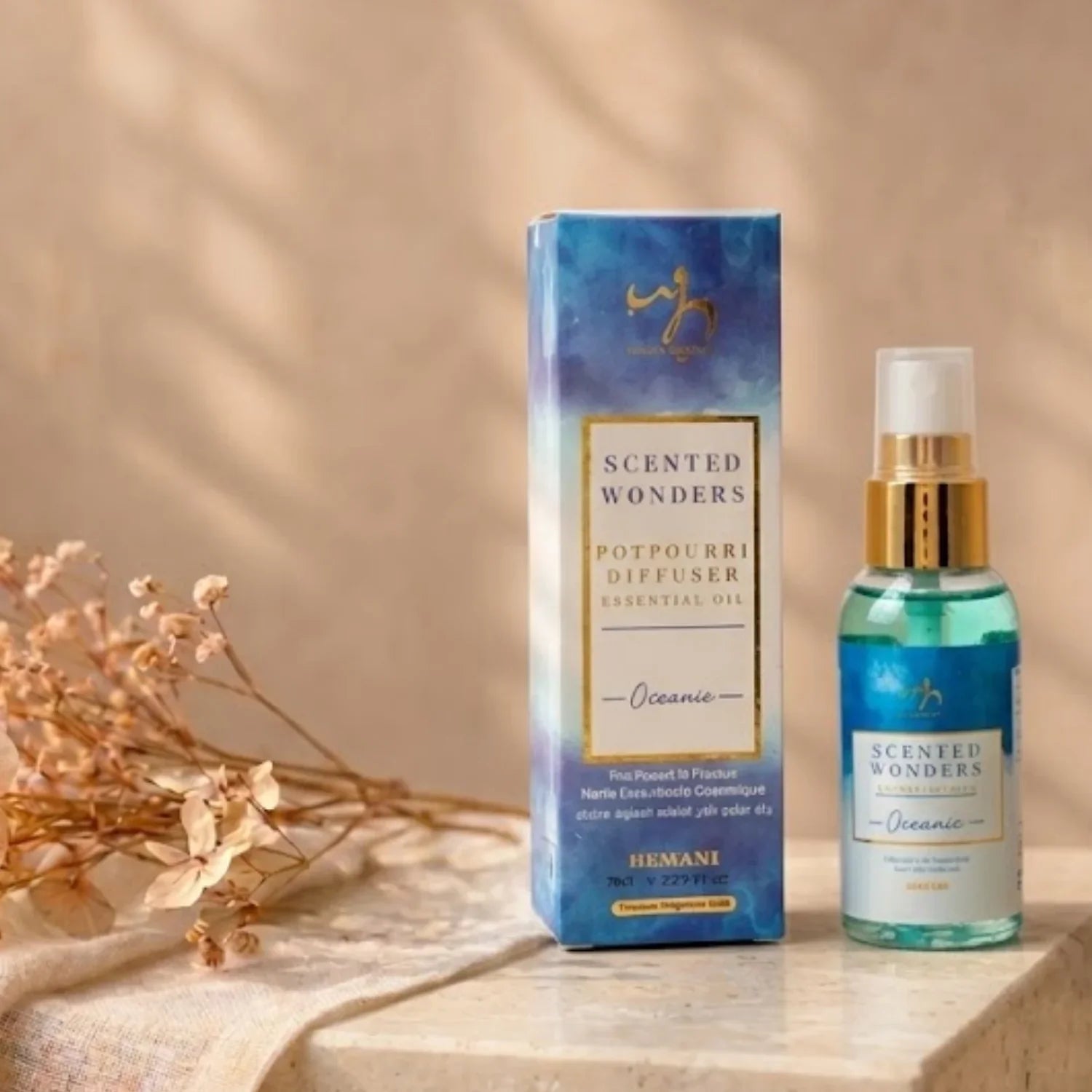 Scented Wonders Oceanic potpourri diffuser essential oil in blue bottle with gold spray nozzle, beside box, on stone surface with dried flowers
